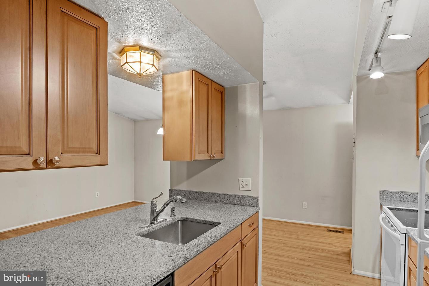 8406 Rainbow Bridge Lane Springfield, VA 22153 - Photo 4 of 8 a kitchen with granite countertop a sink a window and stainless steel appliances