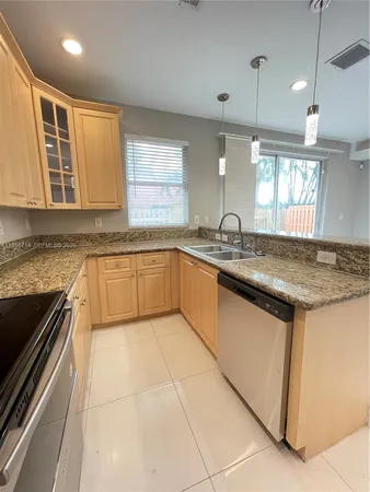 a kitchen with granite countertop stainless steel appliances a sink stove and cabinets