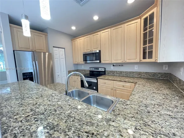 a kitchen with stainless steel appliances granite countertop a stove a sink and a microwave