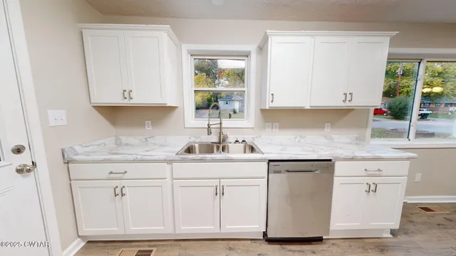 a kitchen with white cabinets and sink