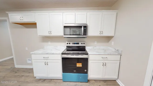 a kitchen with granite countertop white cabinets and stainless steel appliances