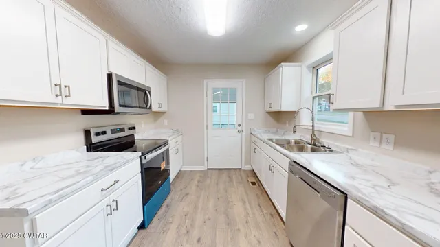 a kitchen with granite countertop a sink a stove top oven a counter space and cabinets