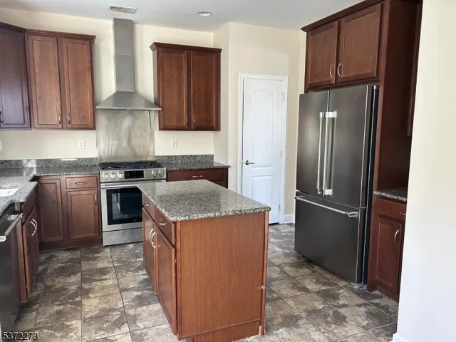 a kitchen with stainless steel appliances granite countertop a refrigerator a stove and a sink