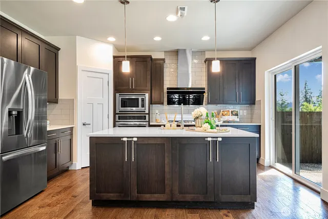 a kitchen with kitchen island granite countertop stainless steel appliances a sink a counter top space cabinets and a center island