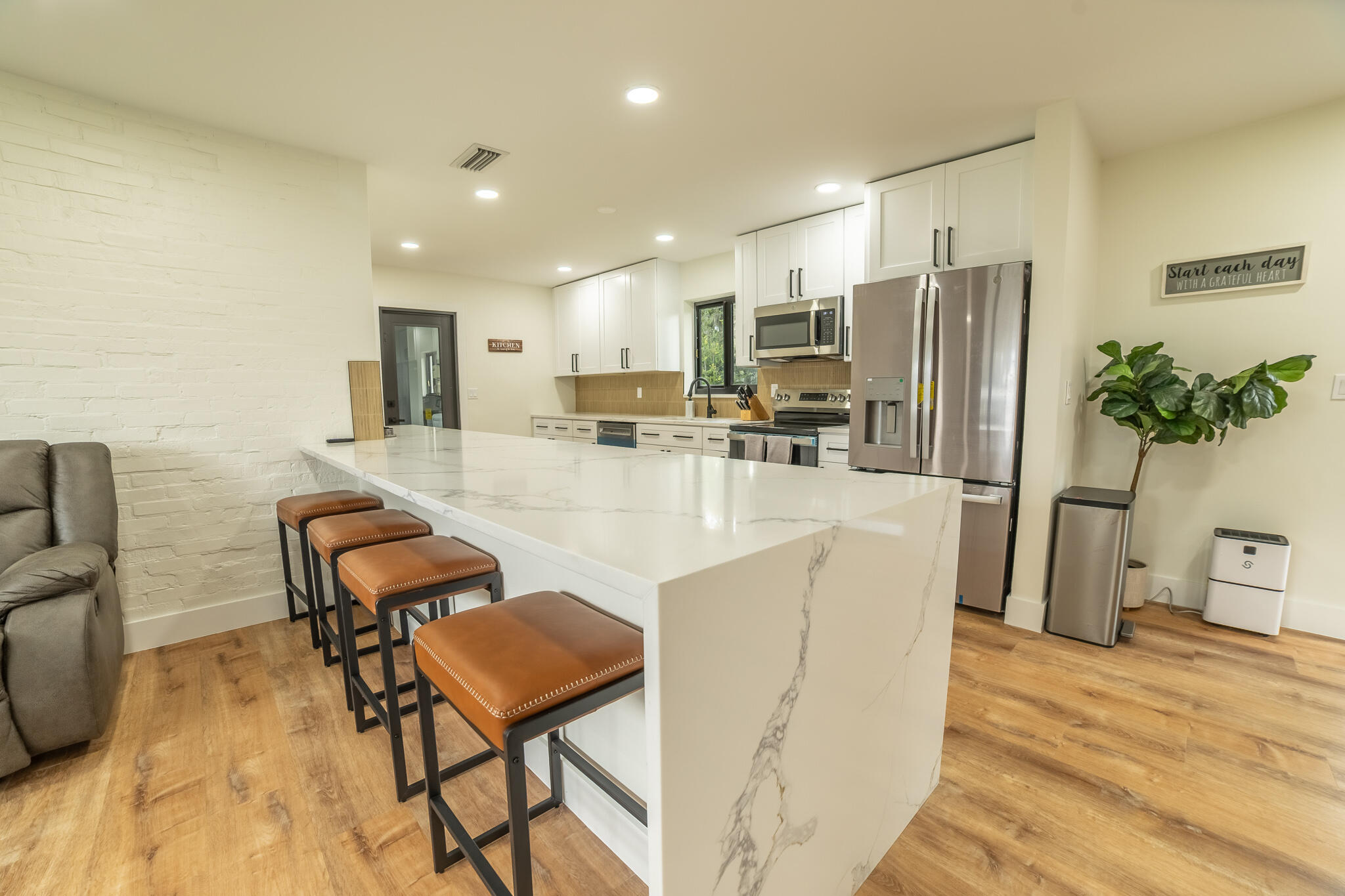 809 Southeast 12th Street Okeechobee, FL 34974 - Photo 7 of 62 a kitchen with stainless steel appliances kitchen island granite countertop a refrigerator a stove a dining table and chairs with wooden floor