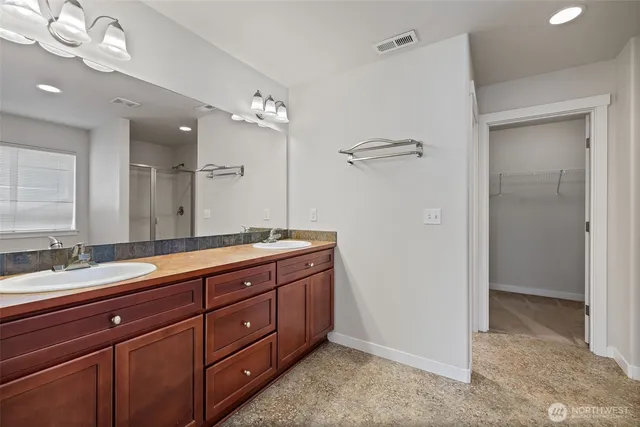 a spacious bathroom with a double vanity sink a large mirror and shower
