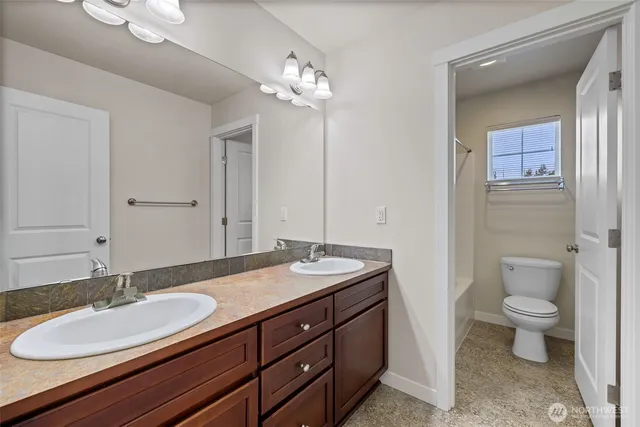 a bathroom with a granite countertop sink a toilet and a mirror