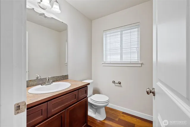 a bathroom with a granite countertop sink toilet a large mirror and a window