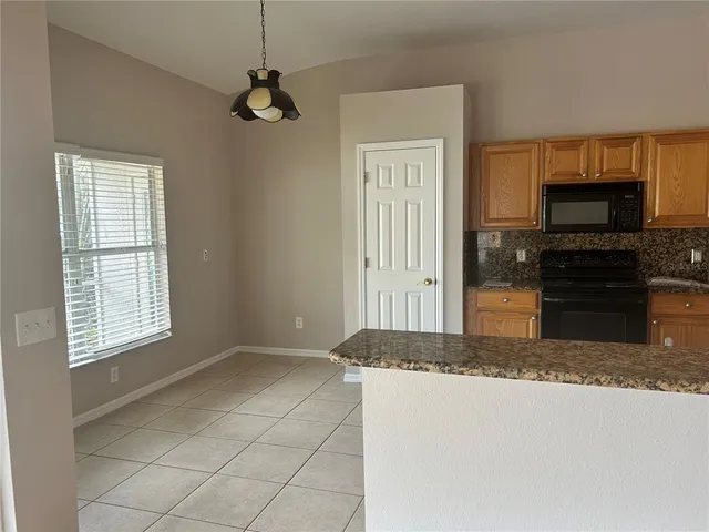 a kitchen with kitchen island granite countertop a sink a stove a microwave a counter top space and cabinets