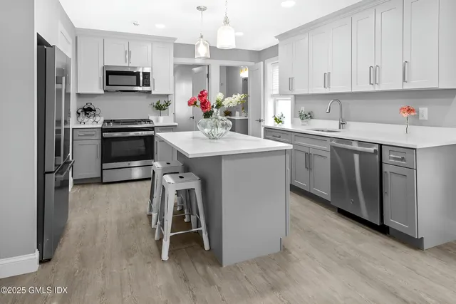 a kitchen with kitchen island granite countertop a sink cabinets and stainless steel appliances