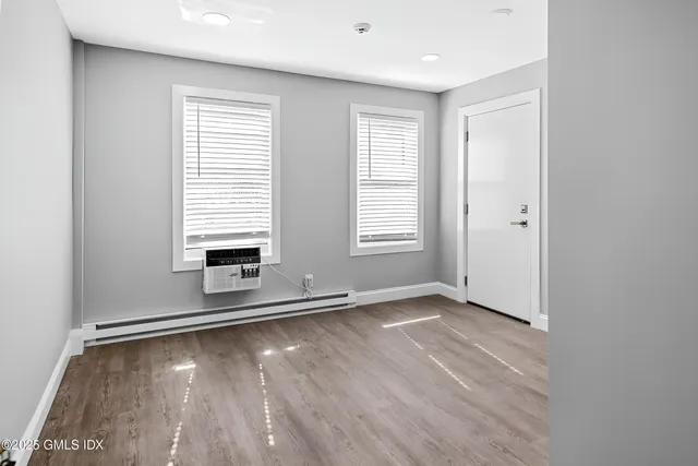 an empty room with wooden floor and windows