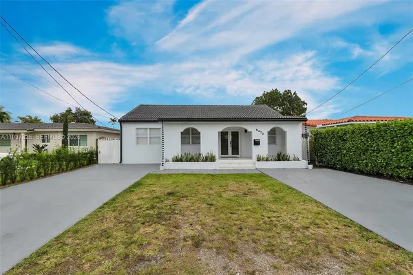 a front view of house with yard and trees in the background