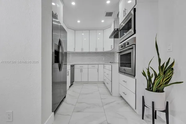 a kitchen with white cabinets and stainless steel appliances