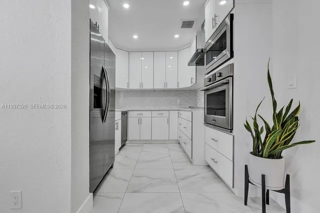 a kitchen with white cabinets and stainless steel appliances