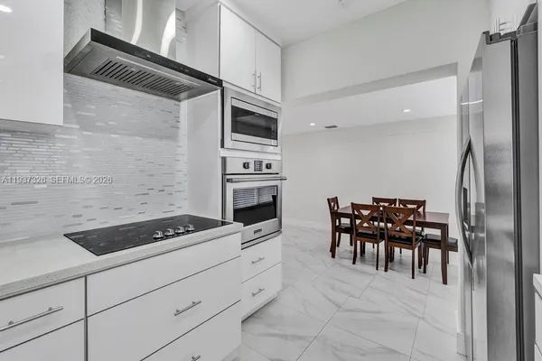 a kitchen with granite countertop a sink cabinets and stainless steel appliances