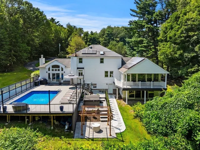an aerial view of a house with swimming pool and large trees