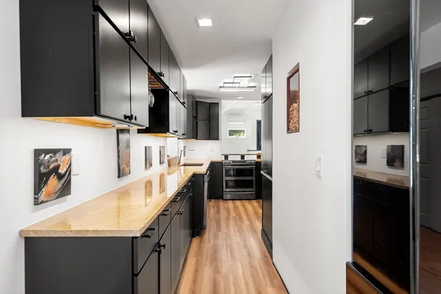 a view of a kitchen with kitchen island wooden floor and stainless steel appliances