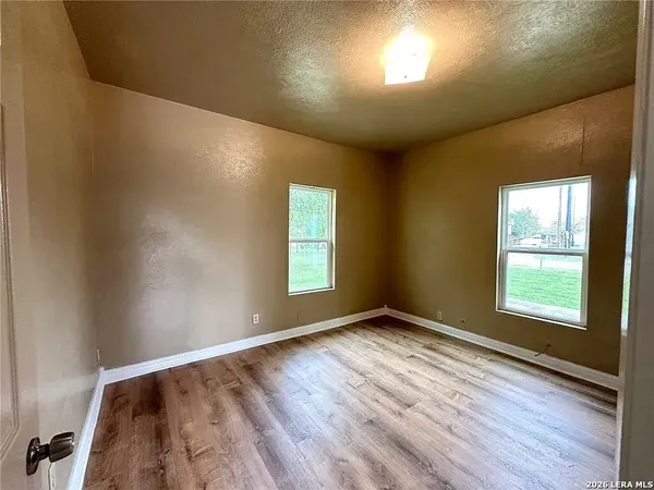 an empty room with wooden floor and windows