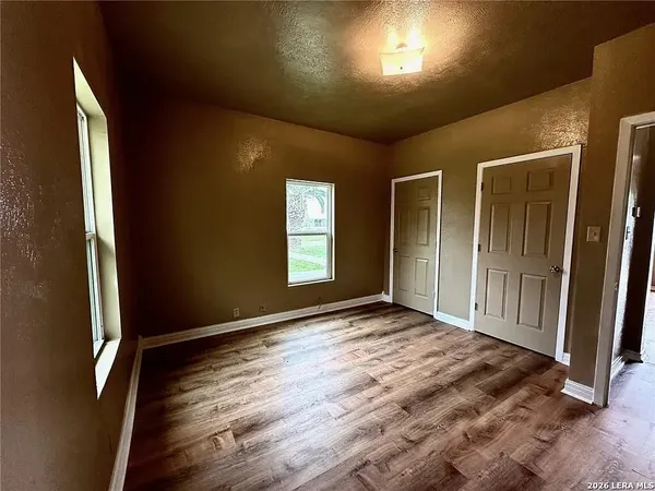 an empty room with wooden floor and windows