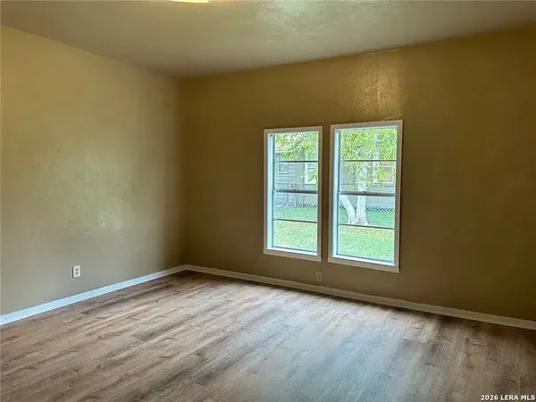 an empty room with wooden floor and windows