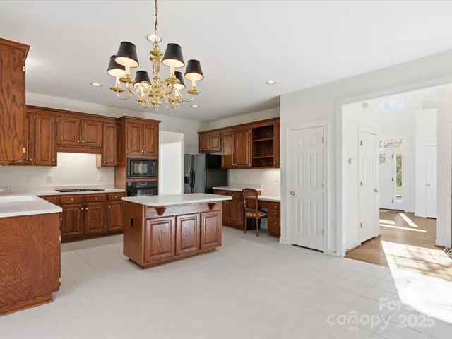 a view of a dining room with furniture a chandelier and kitchen view