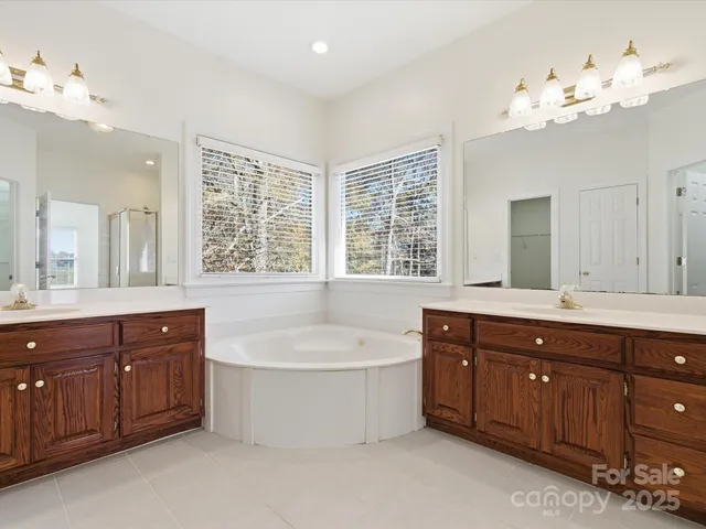 a spacious bathroom with a tub sink double vanity granite and a sink