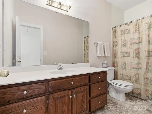 a bathroom with a granite countertop sink a toilet and a mirror