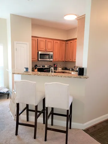 a kitchen with stainless steel appliances granite countertop a table chairs sink and cabinets