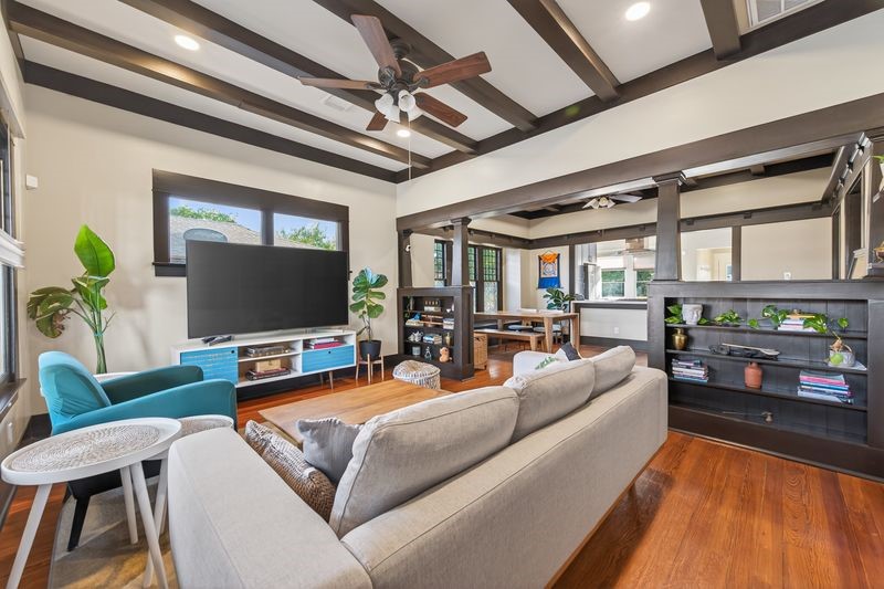 1414 Finch Street Houston, TX 77009 - Photo 4 of 24 The living room is filled with soul and craftsmanship, showcasing beautiful ceiling beams, original millwork, built-ins, and rich wood floors that reflect the home’s historic charm. Every detail was thoughtfully preserved, creating a warm and inviting space full of character and timeless beauty.