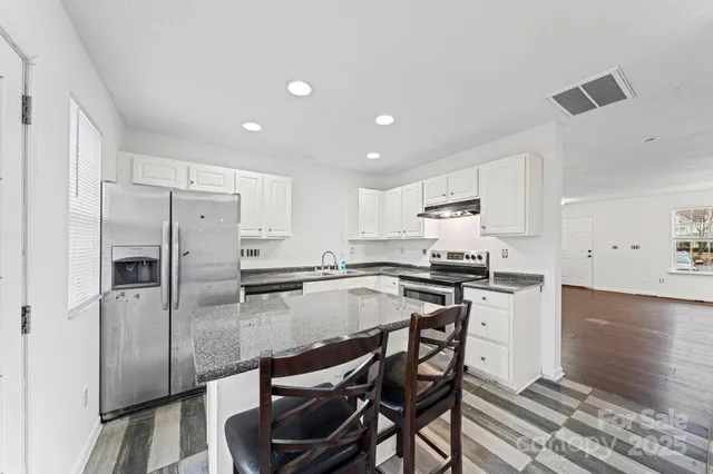 a kitchen with stainless steel appliances granite countertop a stove top oven a refrigerator a sink and a island