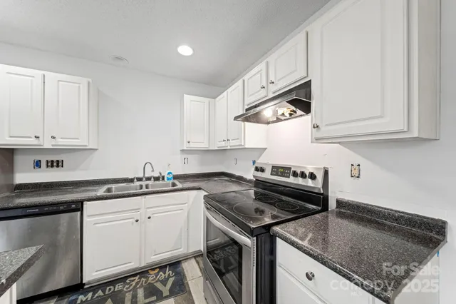 a kitchen with stainless steel appliances granite countertop a sink stove top oven and cabinets