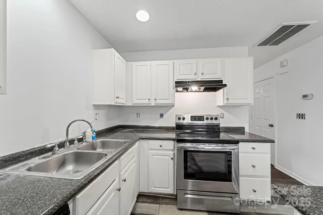 a kitchen with granite countertop a stove sink and cabinets