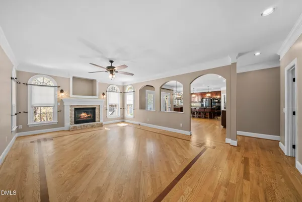 an empty room with wooden floor fan and windows