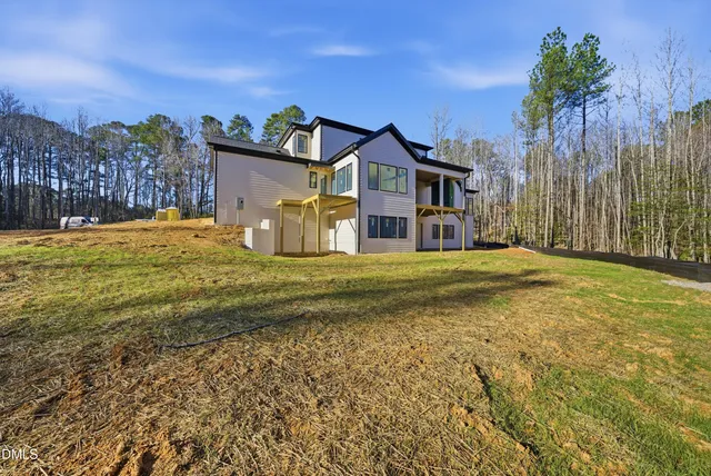 a view of a house with a big yard and large tree