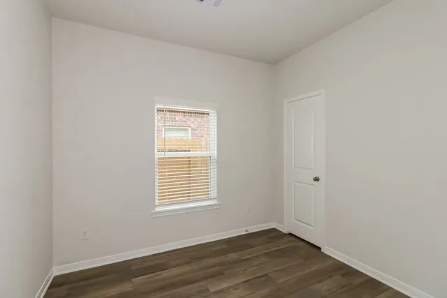 an empty room with wooden floor and a window
