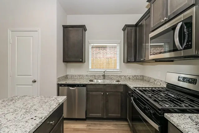 a kitchen with stainless steel appliances granite countertop a sink stove and cabinets