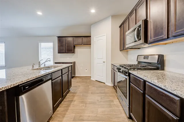a large kitchen with stainless steel appliances kitchen island granite countertop a stove a sink and a refrigerator