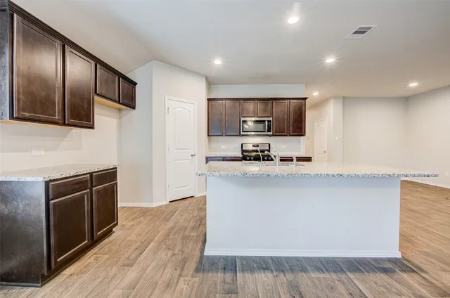 a kitchen with stainless steel appliances kitchen island granite countertop a stove a sink and a microwave