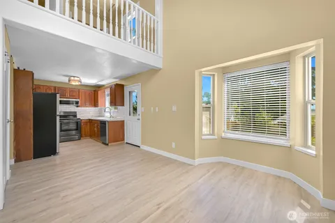 a view of kitchen with stainless steel appliances wooden floor and windows