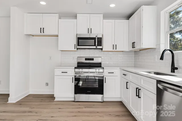 a kitchen with cabinets stainless steel appliances and wooden floor