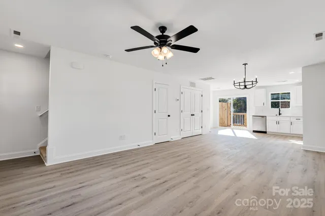 a view of empty room with wooden floor and ceiling fan