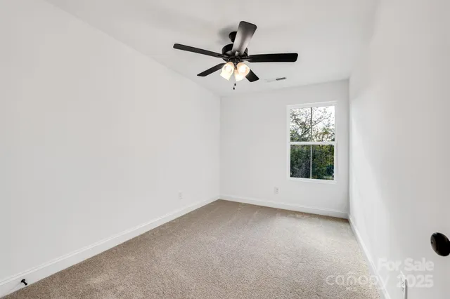an empty room with a ceiling fan and a window