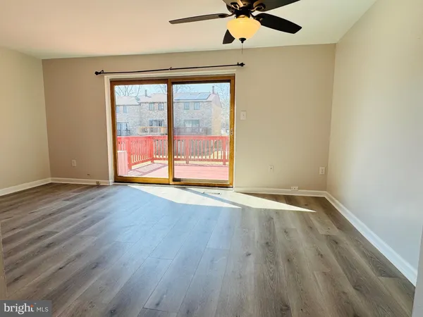 an empty room with wooden floor fan and windows