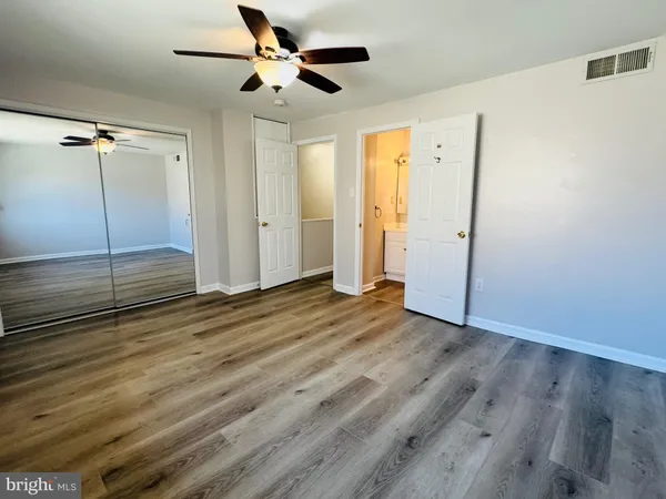 a view of empty room with wooden floor and fan