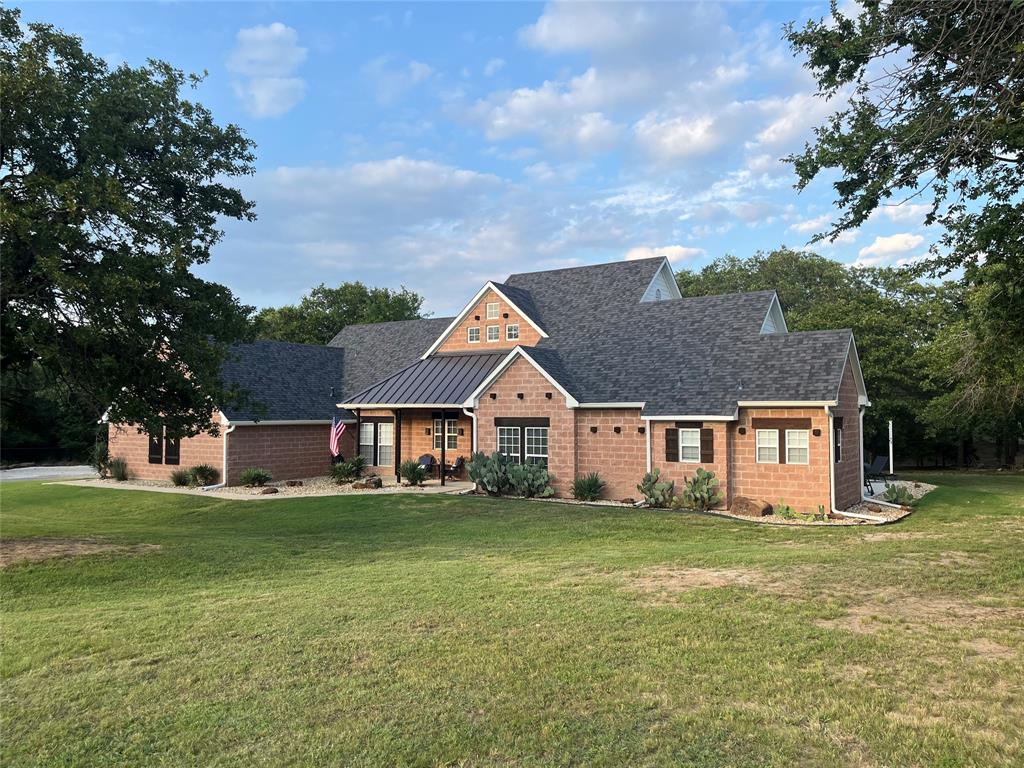 a front view of house with yard and trees in the background