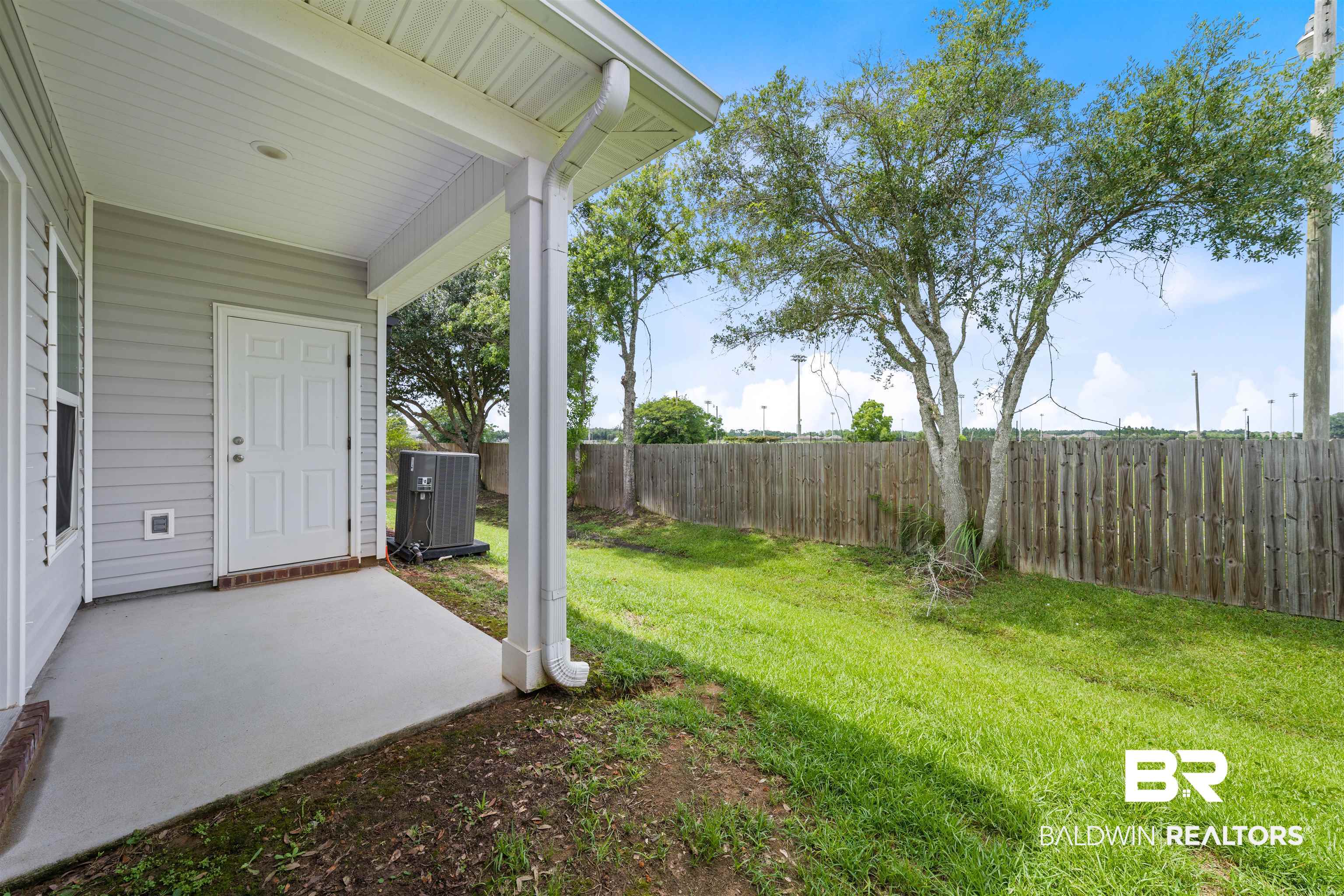 2651 South Juniper Street, Unit 1801 Foley, AL 36535 - Photo 16 of 16 Covered concrete patio with white paneled door, light gray siding, and a spacious green lawn
