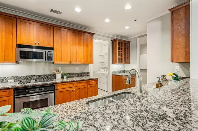 a kitchen with stainless steel appliances granite countertop wooden cabinets a stove top oven a sink and dishwasher