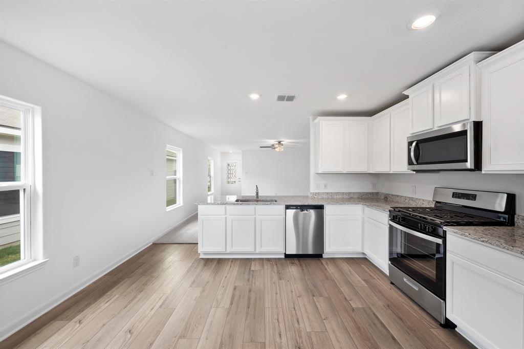 585 Aplite Pass Maxwell, TX 78656 - Photo 6 of 13 a kitchen with granite countertop a stove top oven a sink dishwasher and a refrigerator with wooden floor