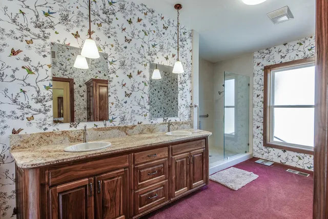 a bathroom with a granite countertop sink a mirror and a shower