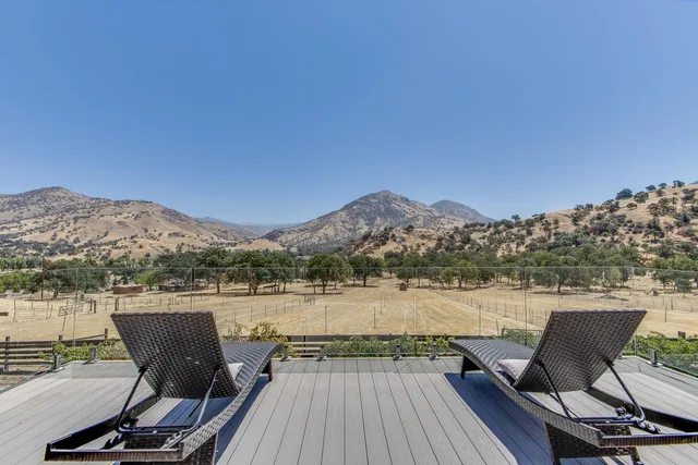 a view of a chairs and table on wooden deck with lake view